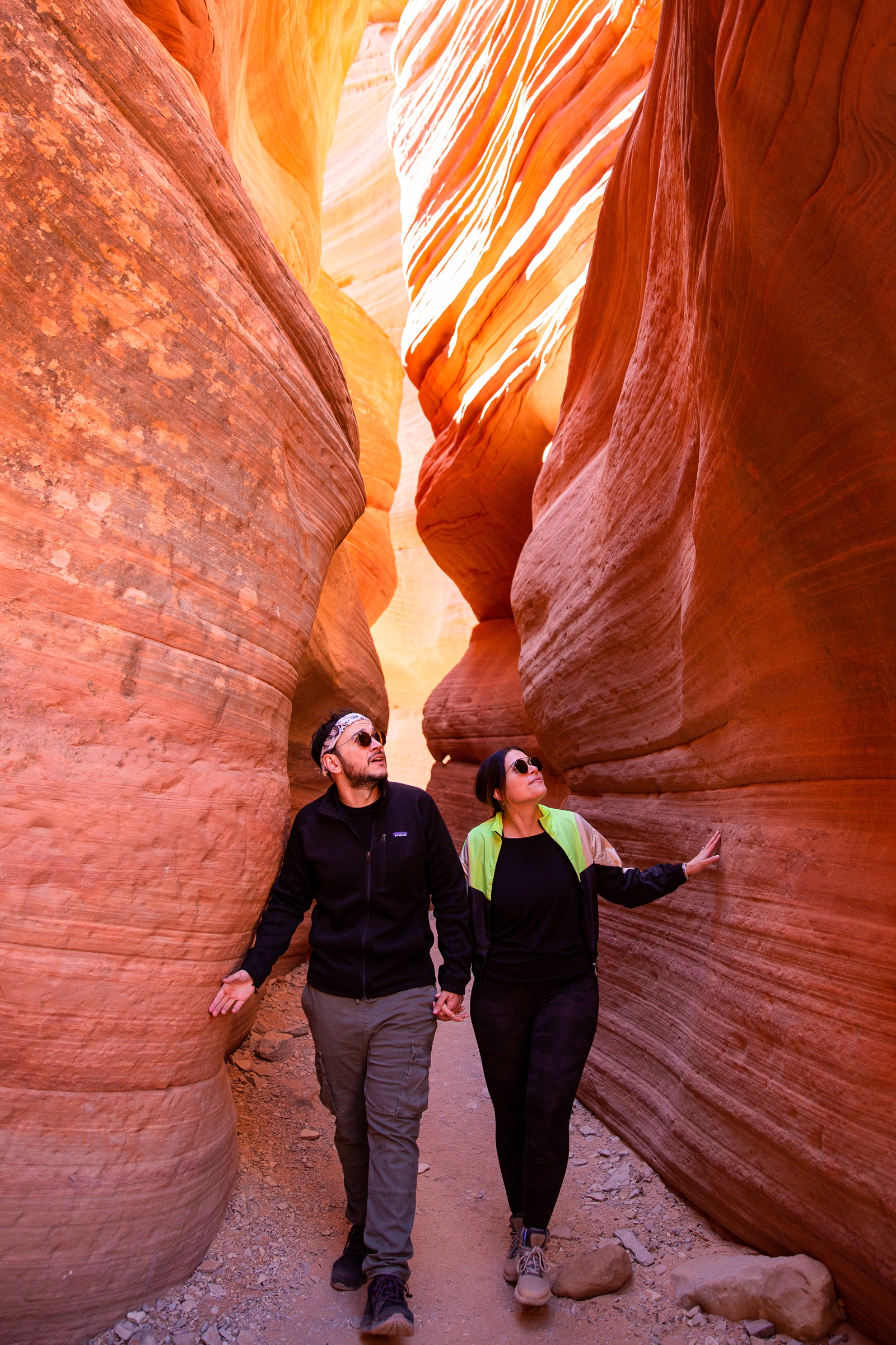 engaged Couple holding hands while walking through the Utah slot canyon during their hiking adventure through the antelope canyon