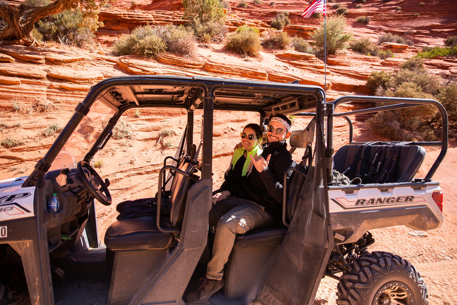 a newly engaged couple posing and smiling for a picture on the ATV in Utah Slot Canyon during their adventurous hike