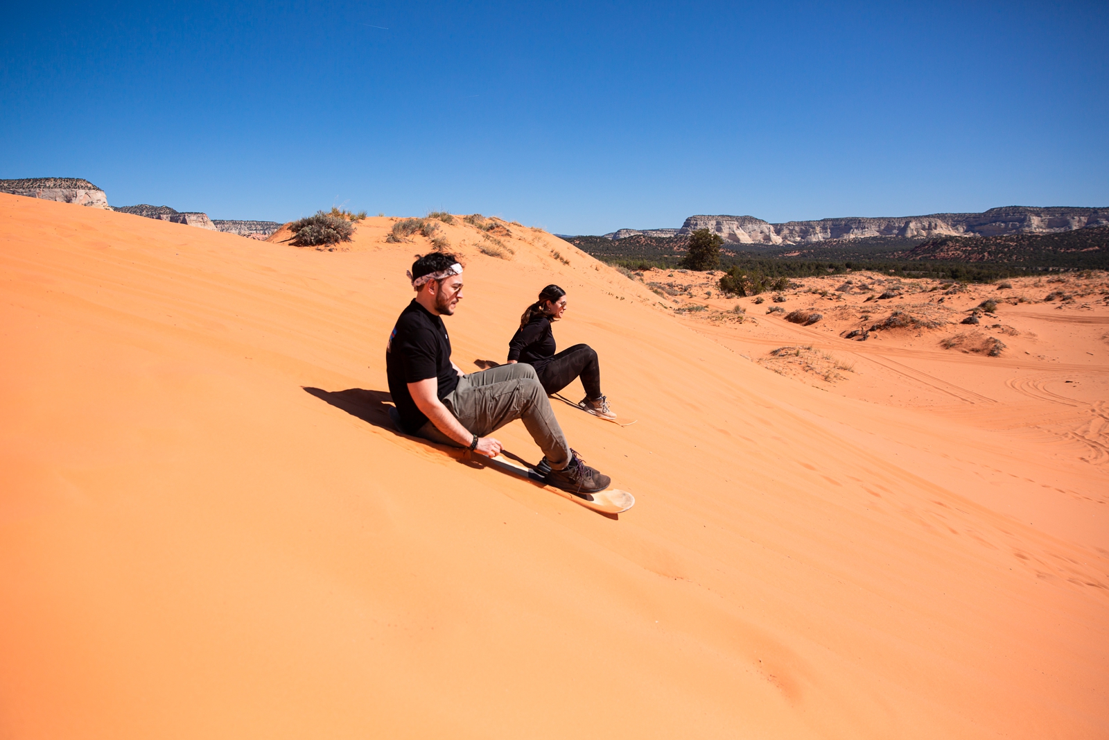 a newly engaged couple learning on to sandboard from their tour guide by the Utah slot canyons