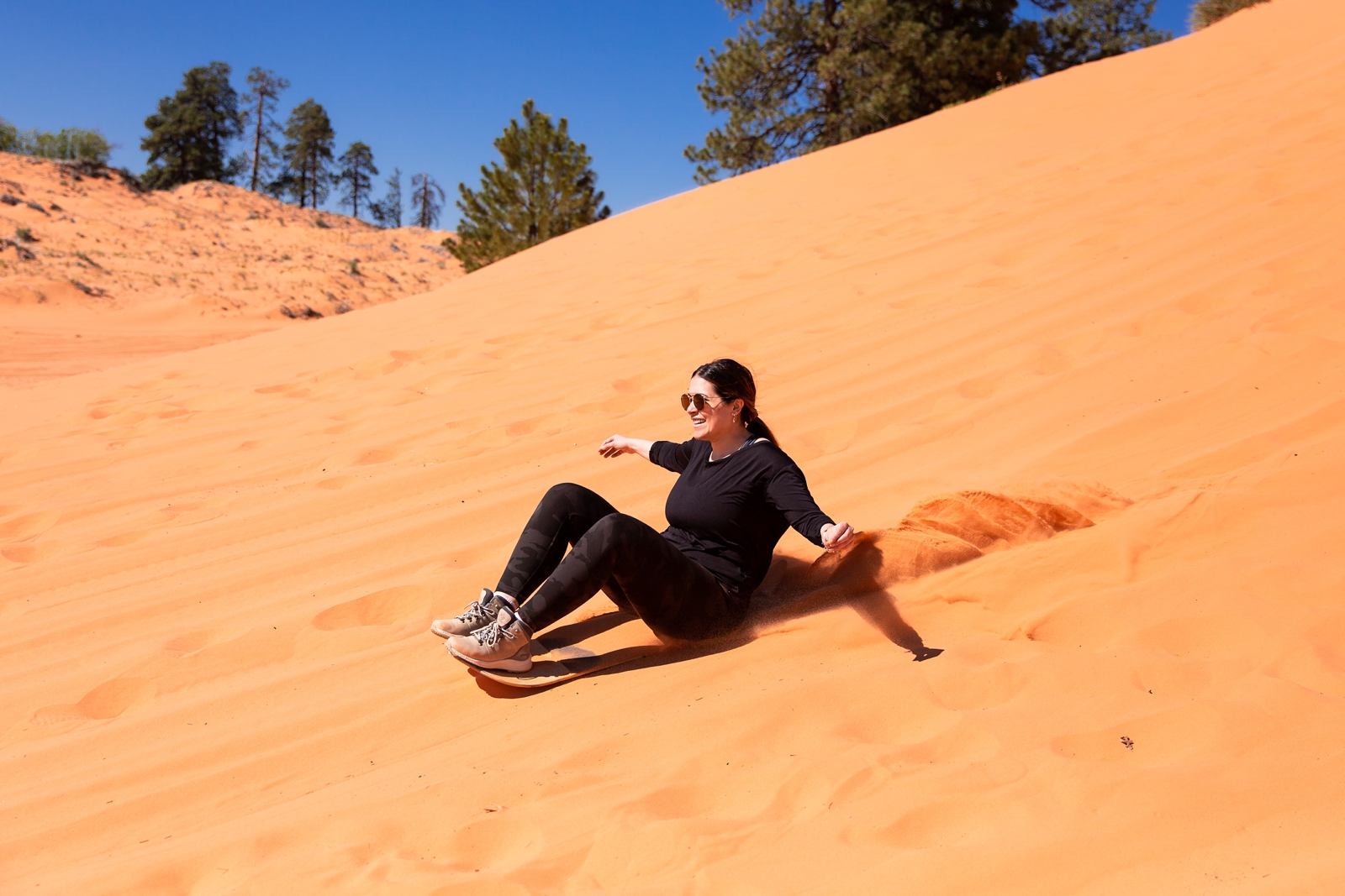 a newly engaged couple sandboarding by the Utah slot canyons