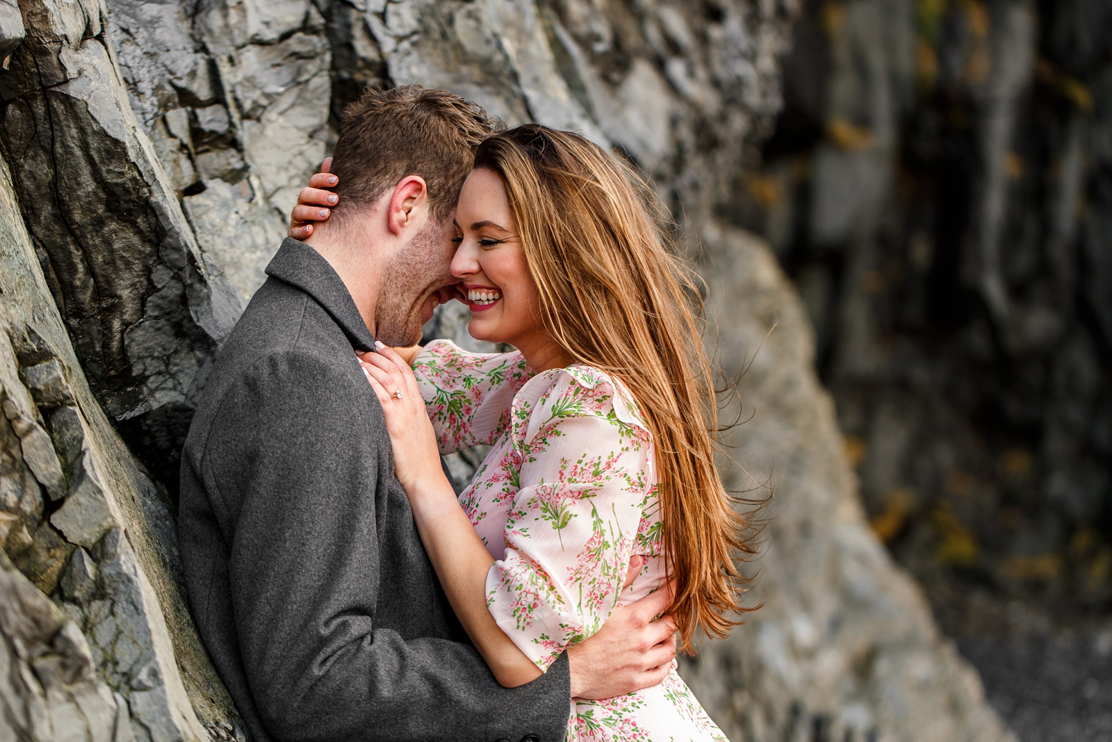Cuddling smiling couple by basalt columns at their destination Iceland engagement session near Vik, Iceland