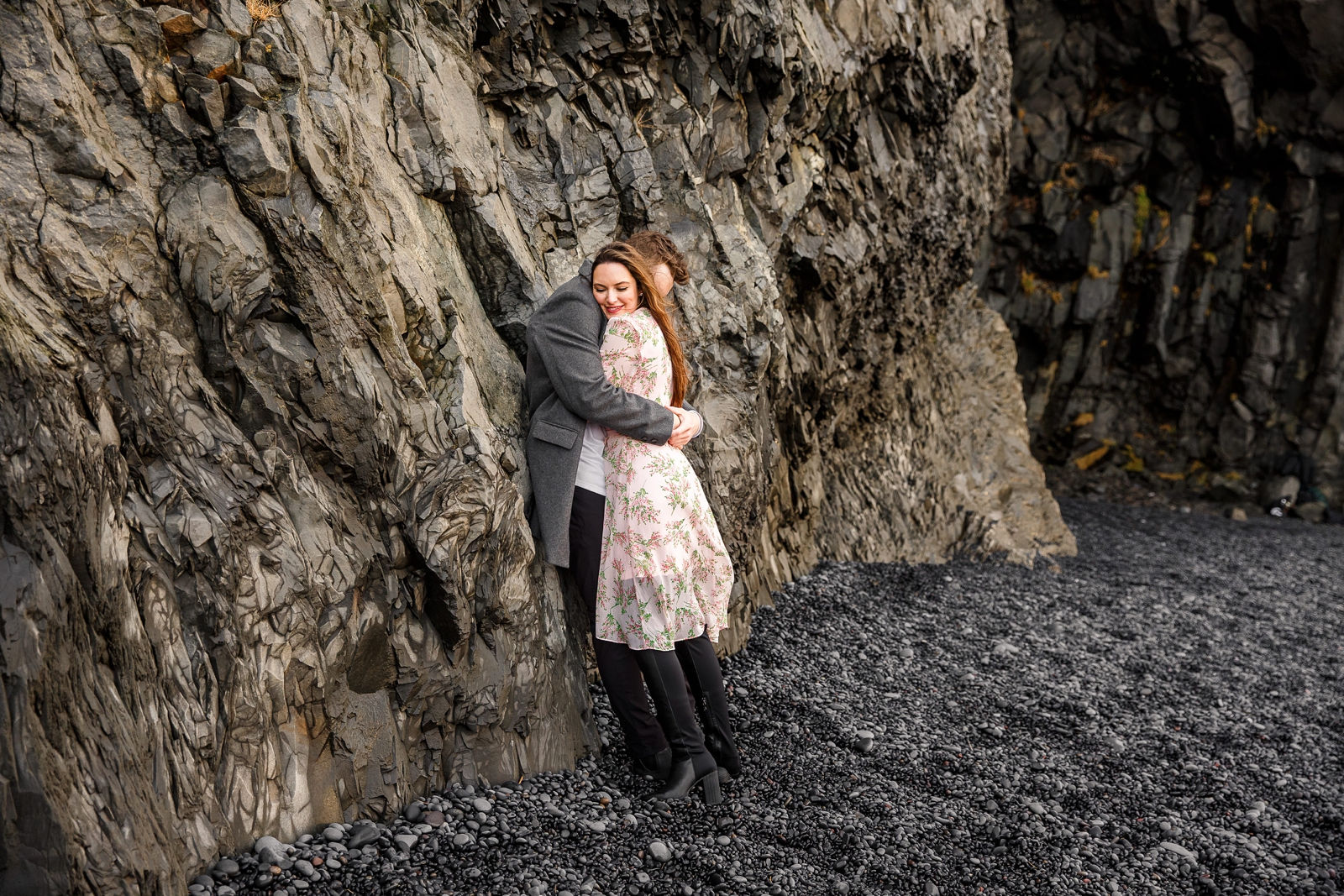 Cuddling couple by basalt columns at their destination Iceland engagement session near Vik, Iceland