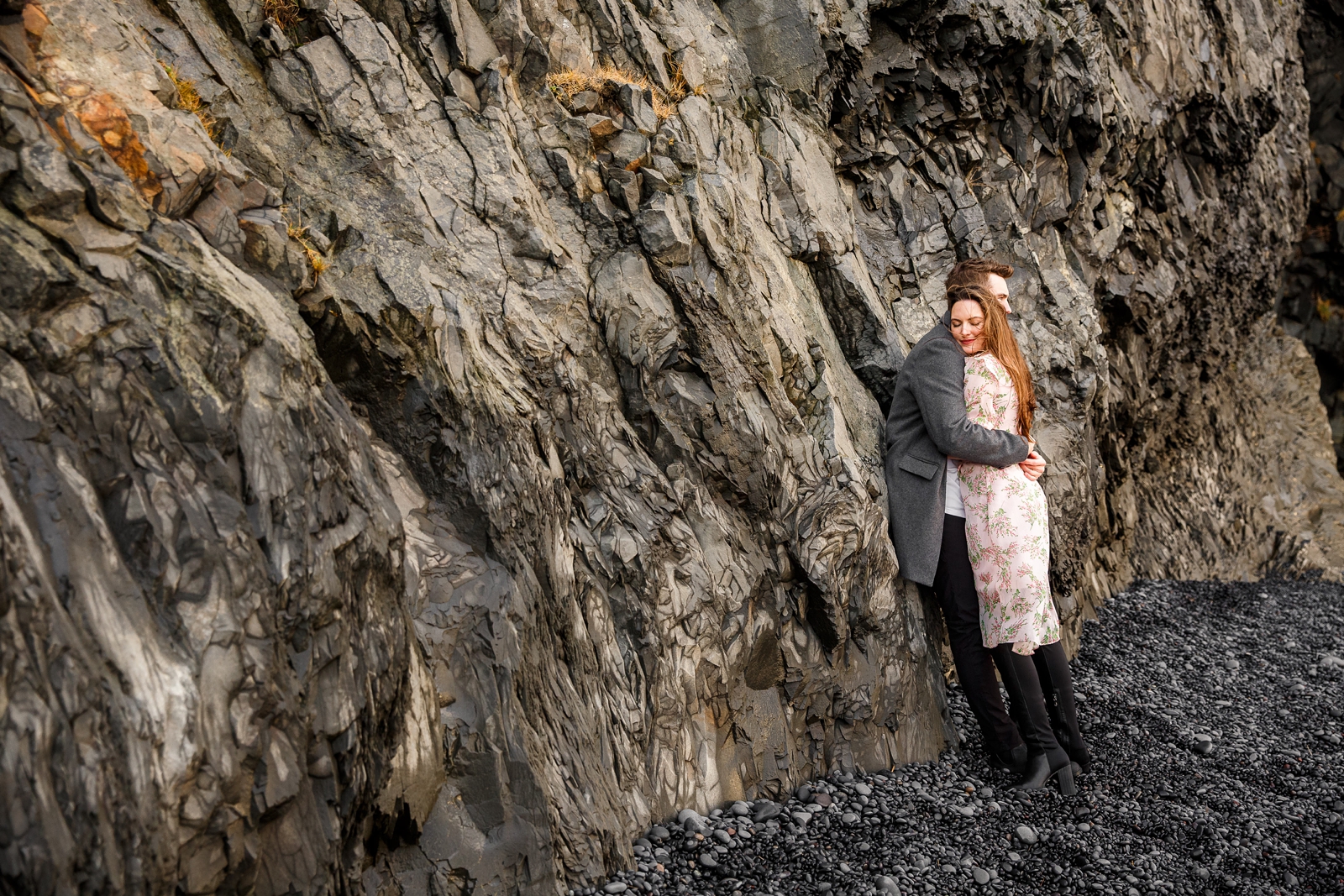 Cuddling couple by basalt columns at their destination Iceland engagement session near Vik, Iceland