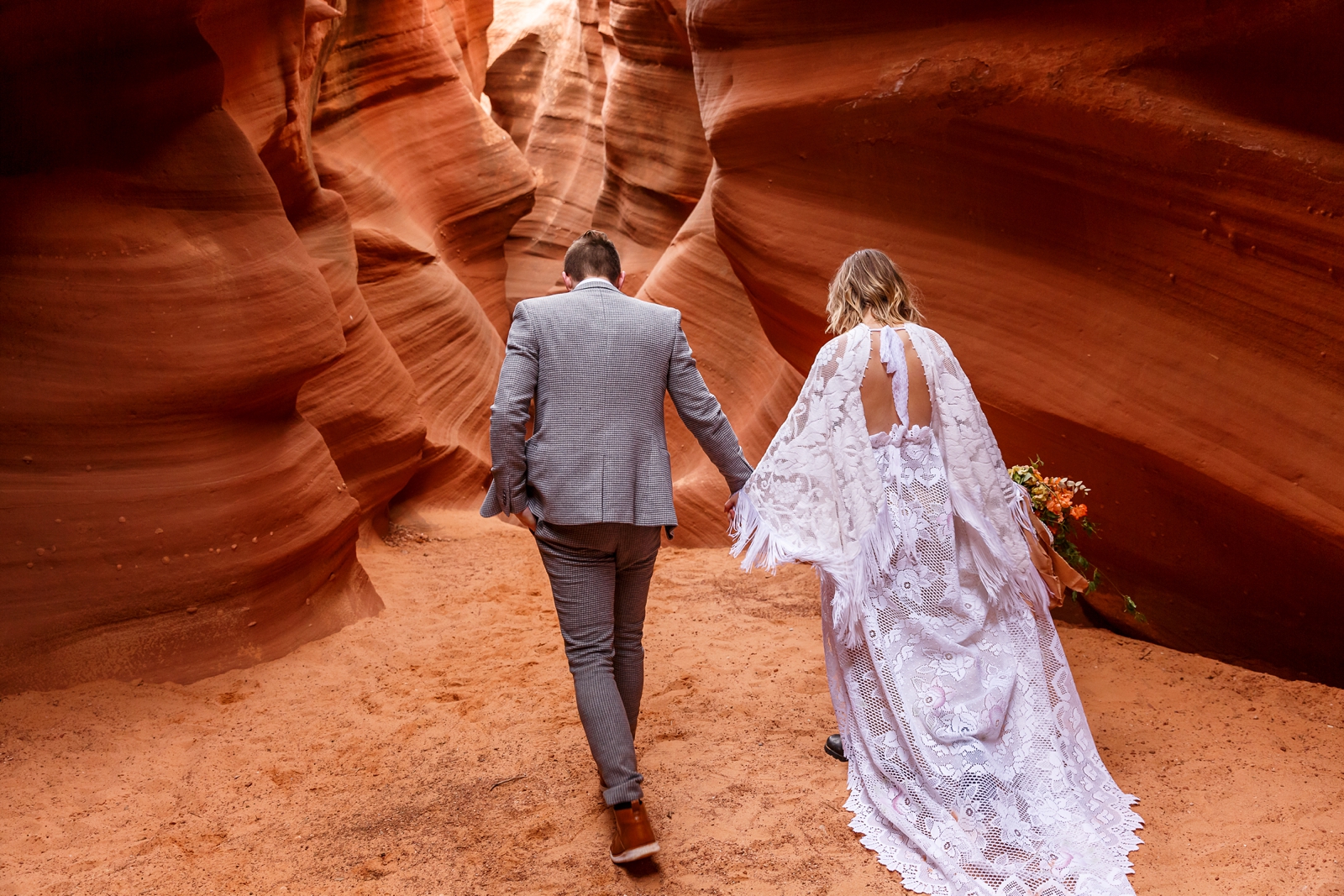 A beautiful in-love couple holding hands during their adventurous slot canyon elopement in Waterholes Canyon near Navajo Nation in Page Arizona