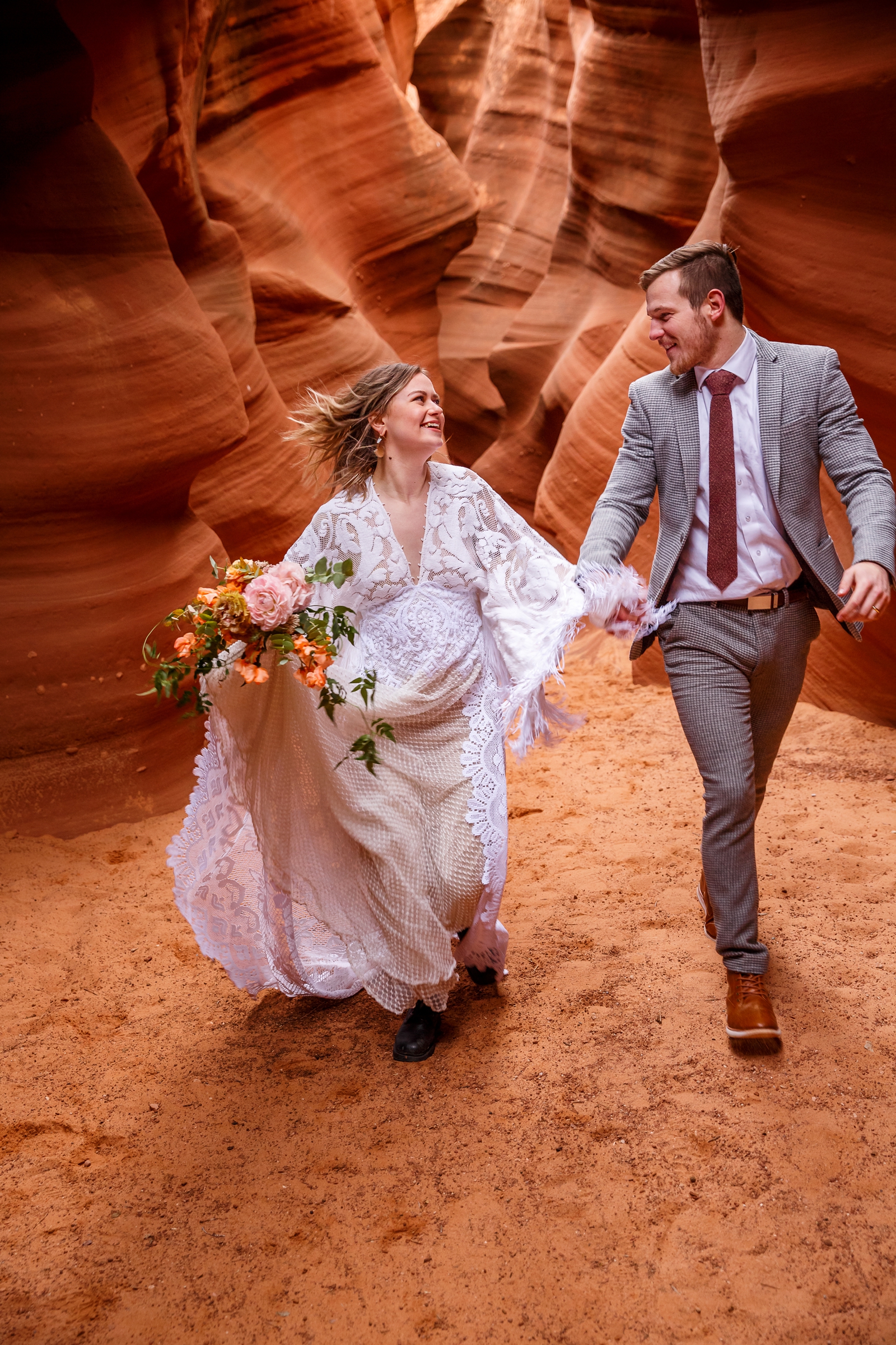 A beautiful in-love couple holding hands during their adventurous slot canyon elopement in Waterholes Canyon near Navajo Nation in Page Arizona