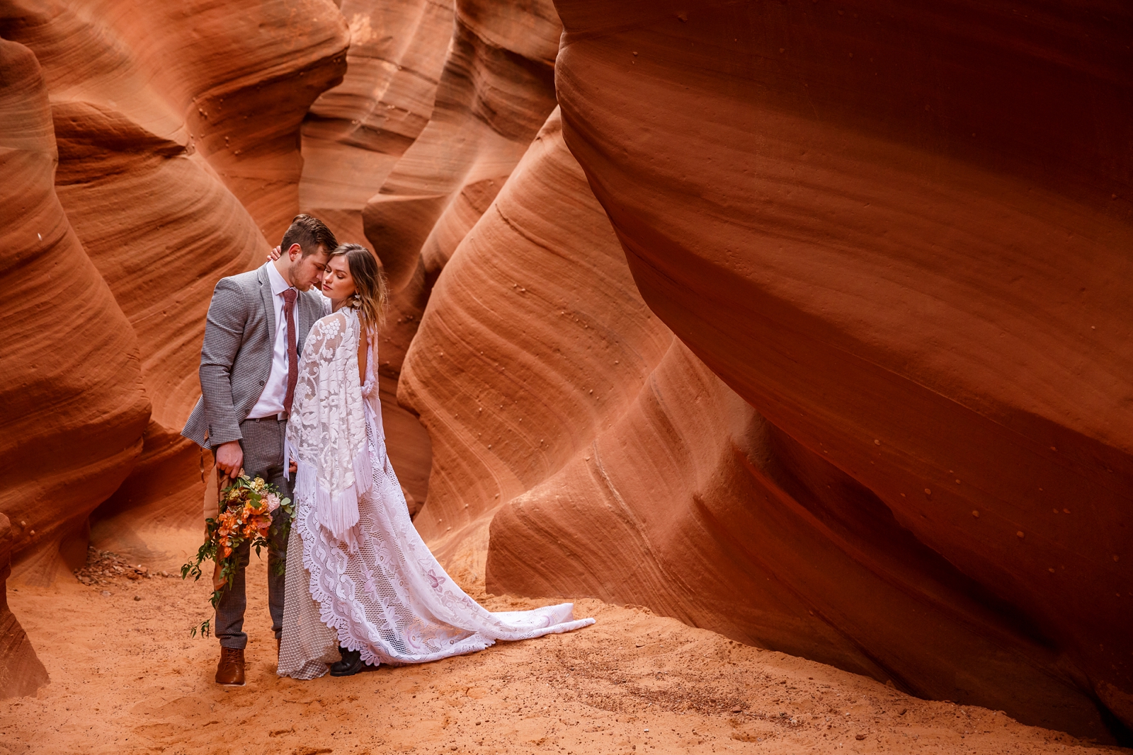 A boho in-love couple embracing during their red rock slot canyon elopement in Waterholes Canyon near Horseshoe Bend in Page Arizona