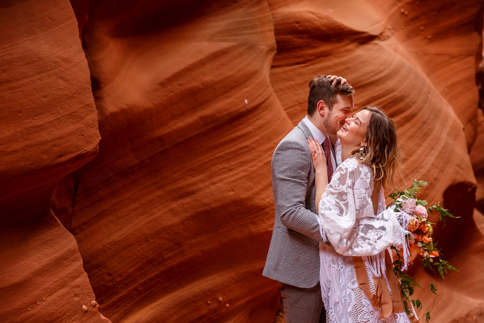 A sweet in-love couple having fun during their winter slot canyon elopement in Waterholes Canyon near Lake Powell in Page Arizona