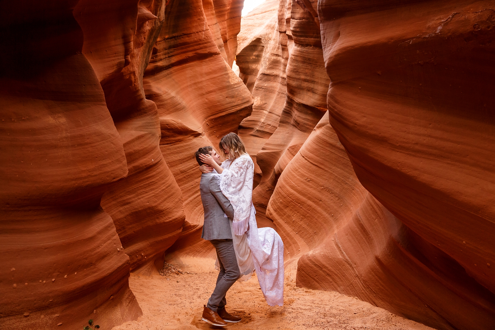 A sweet in-love couple having fun during their winter slot canyon elopement in Waterholes Canyon near Lake Powell in Page Arizona