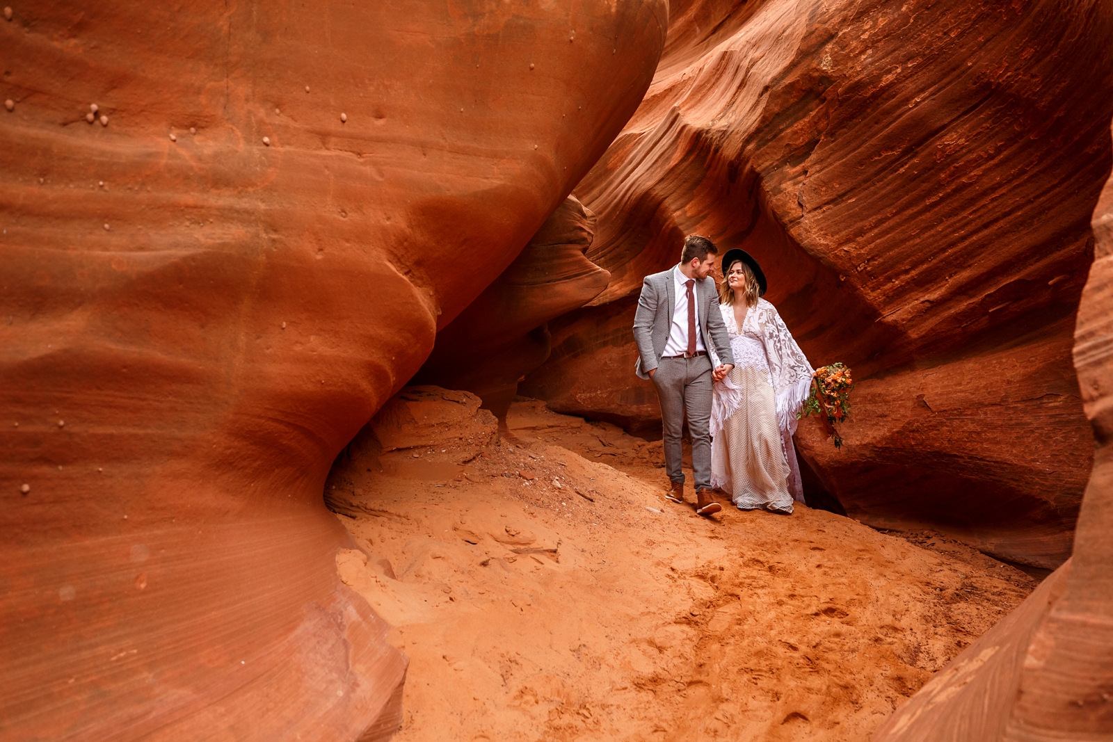 A fun boho couple looking at each other during their adventurous winter slot canyon elopement in Waterholes Canyon near Navajo Nation in Page Arizona