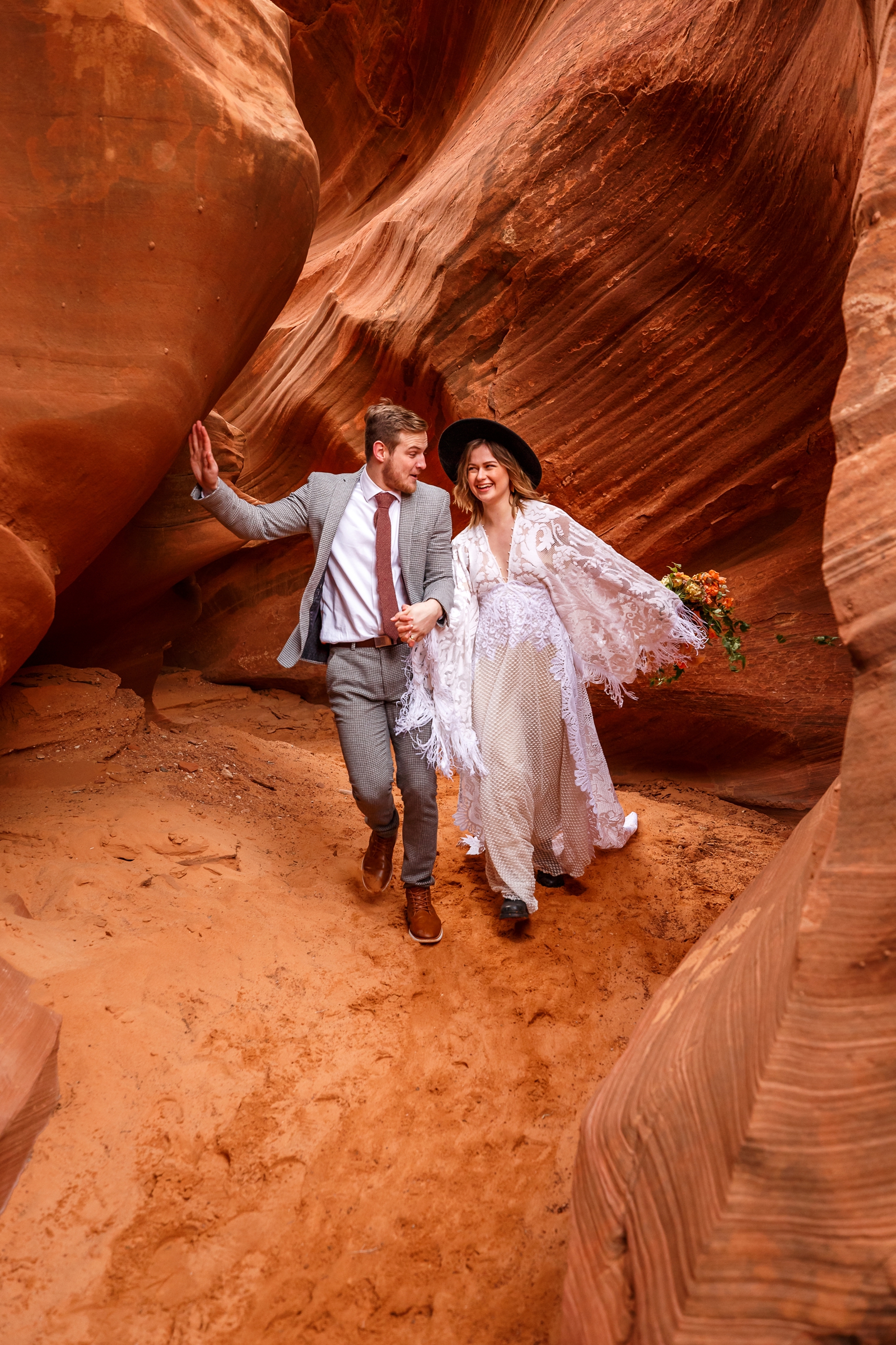 A fun boho couple looking at each other during their adventurous winter slot canyon elopement in Waterholes Canyon near Navajo Nation in Page Arizona