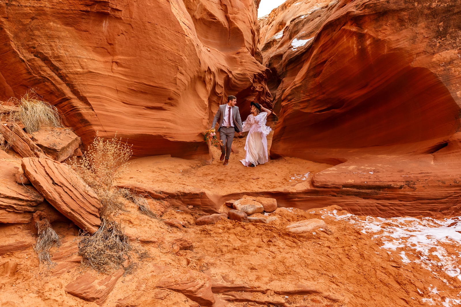 A fun boho couple laughing with each other during their adventurous winter slot canyon elopement in Waterholes Canyon near Horseshoe Bend in Page Arizona