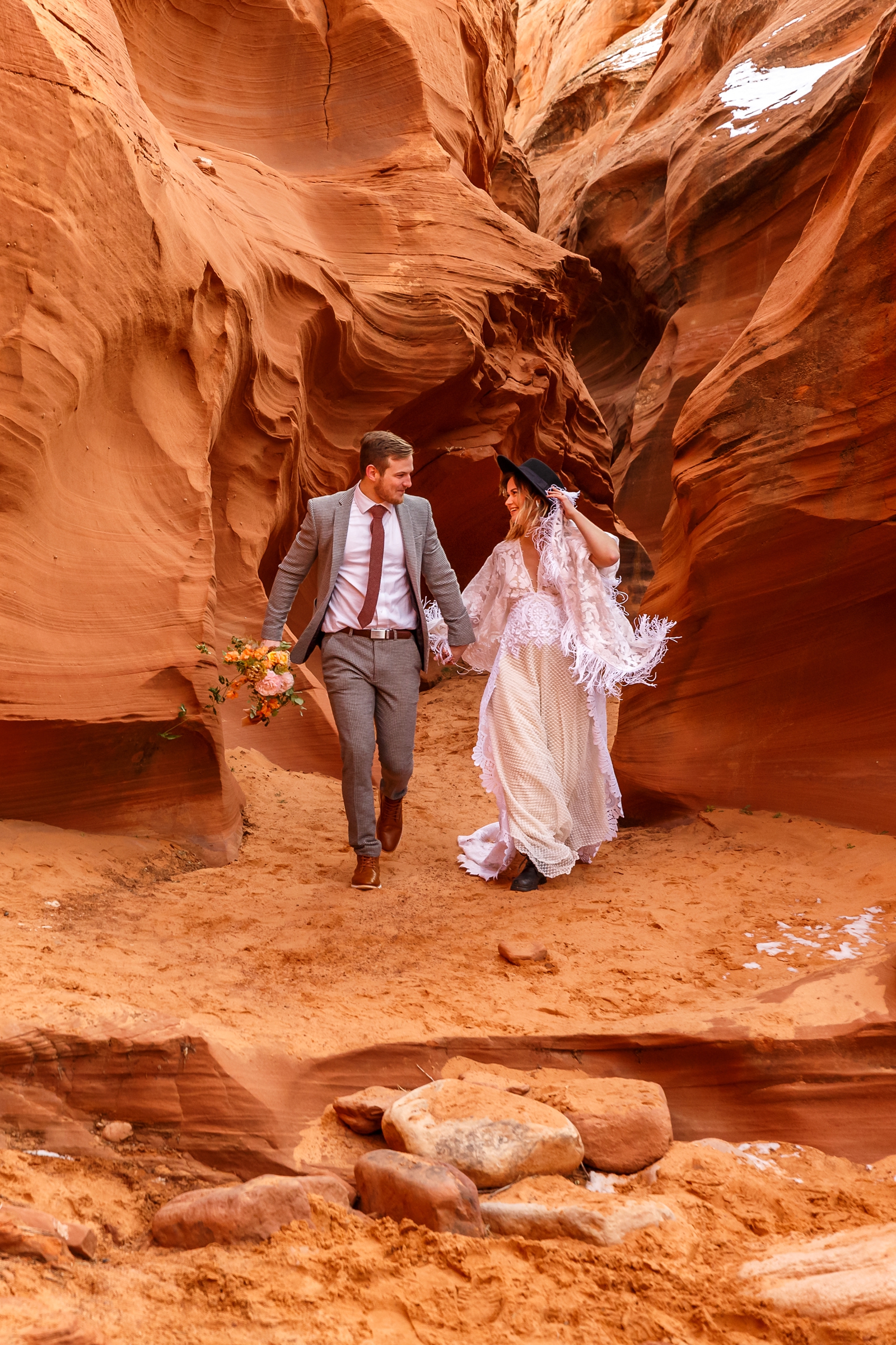 A fun boho couple laughing with each other during their adventurous winter slot canyon elopement in Waterholes Canyon near Horseshoe Bend in Page Arizona
