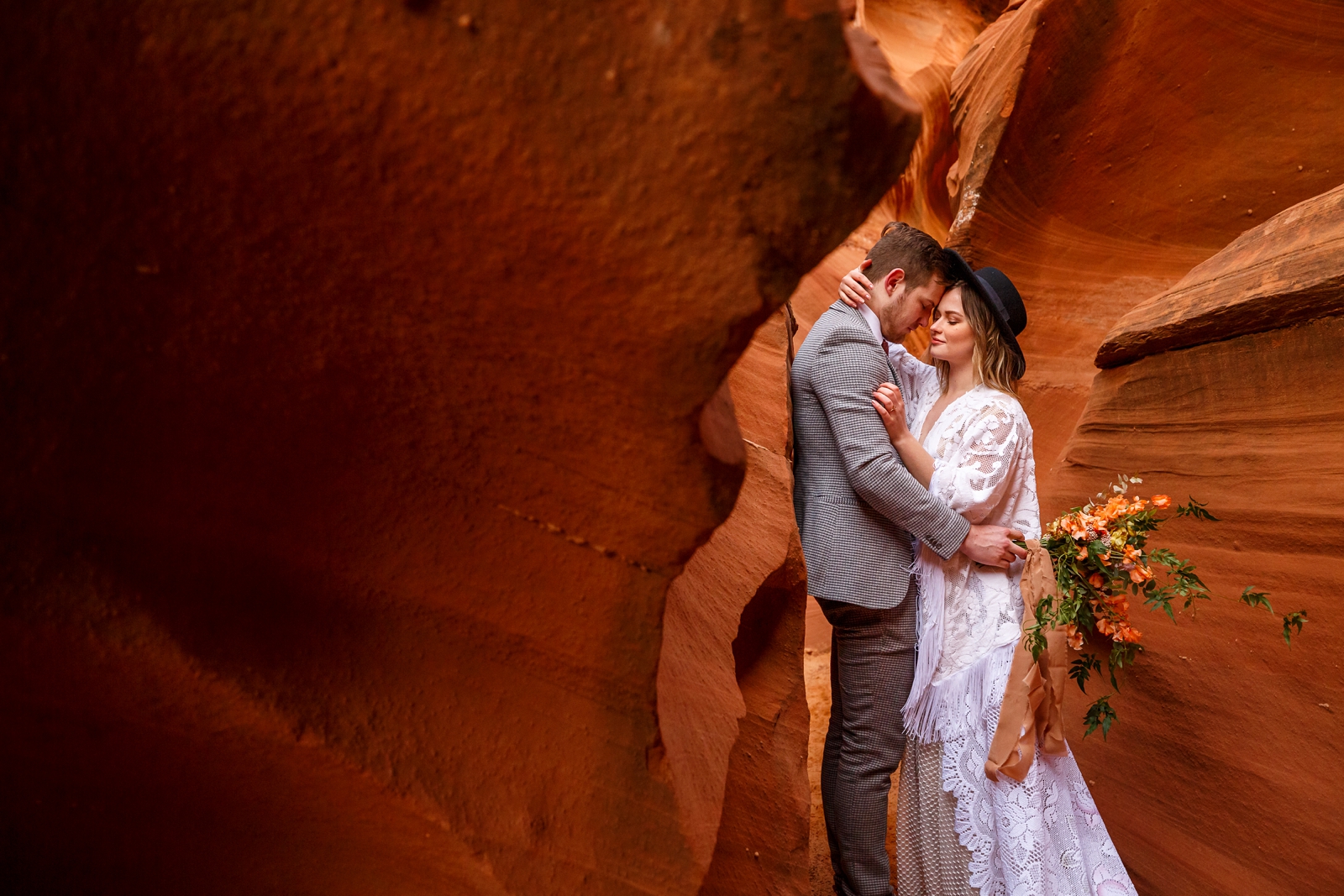 A fun boho couple embracing each other during their adventurous winter slot canyon elopement in Waterholes Canyon near Lake Powell in Page Arizona