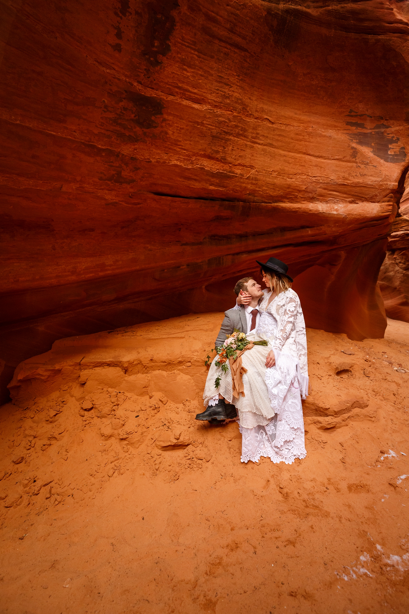 A fun boho couple embracing each other during their adventurous winter slot canyon elopement in Waterholes Canyon near Lake Powell in Page Arizona