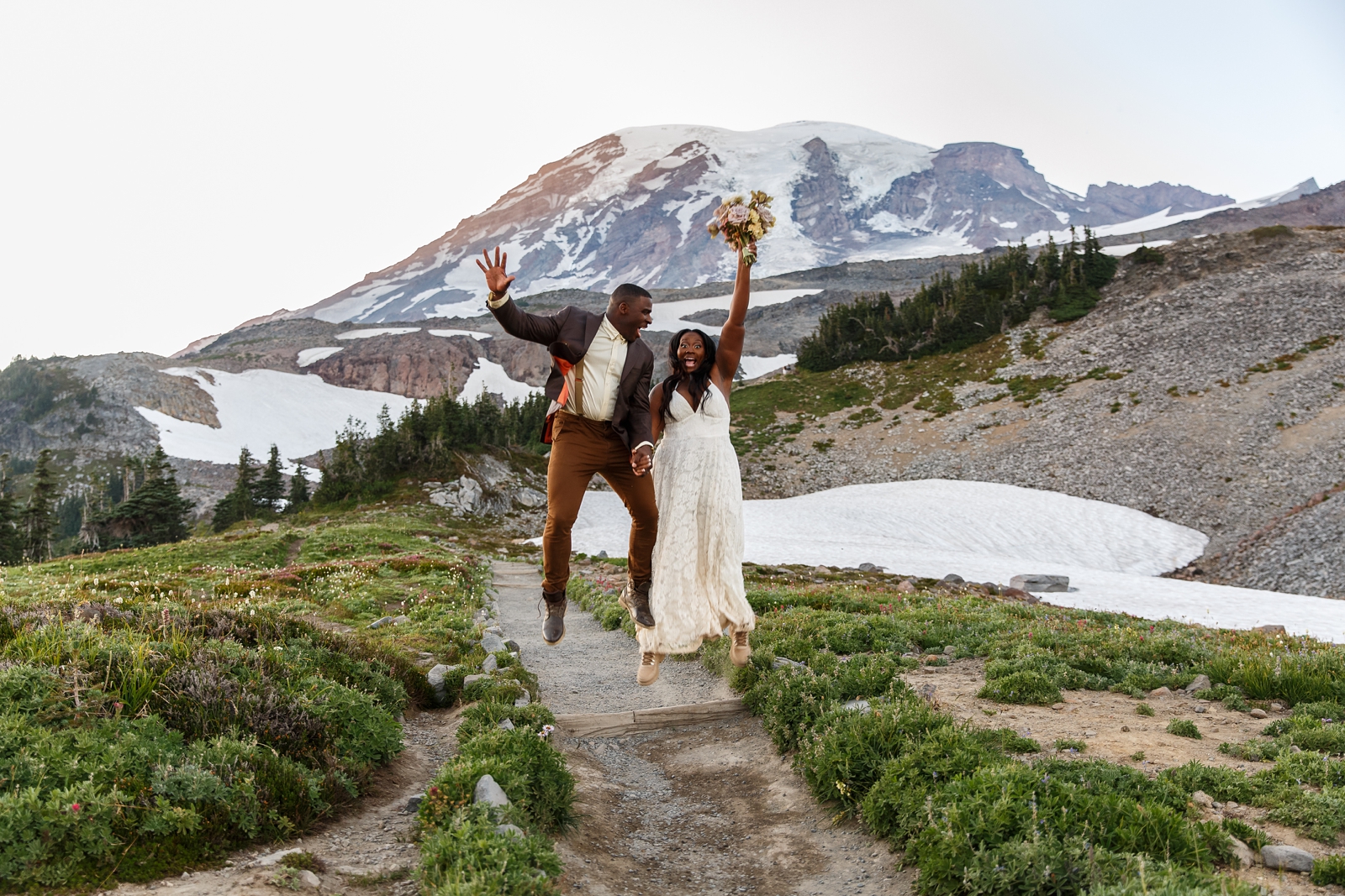 This couple jump in the air during their Mount Rainier Hiking elopement in Washington.