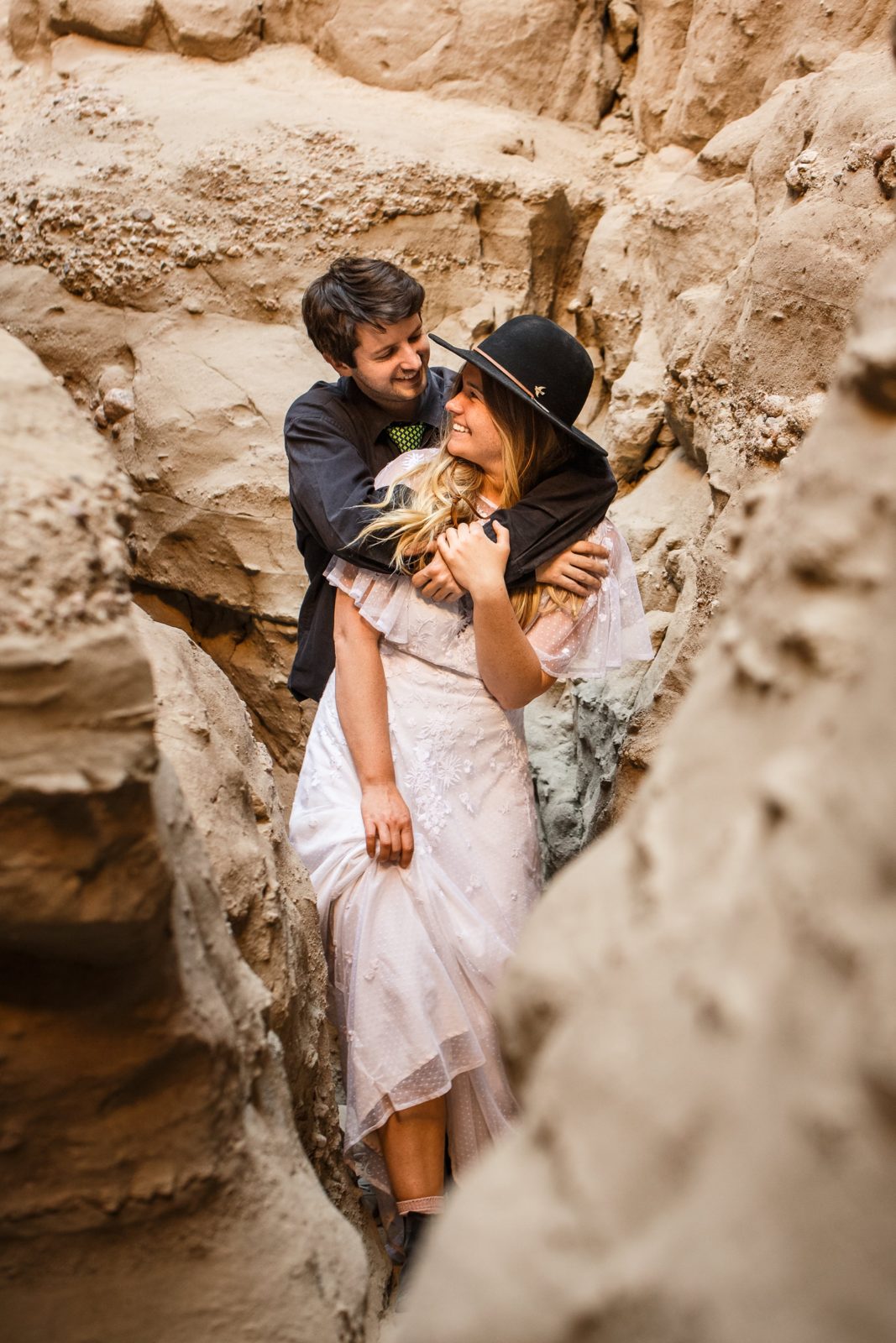 Two eloping partners embrace during their outdoor hiking adventure slot canyon elopement near Mecca Hills California.