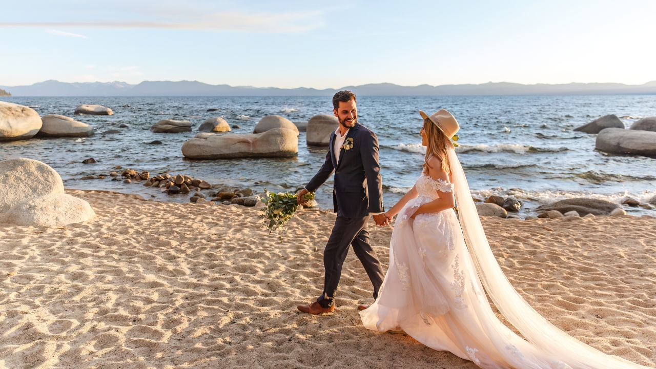 Photo of bride and groom walking along the beach at Lake Tahoe for their elopement