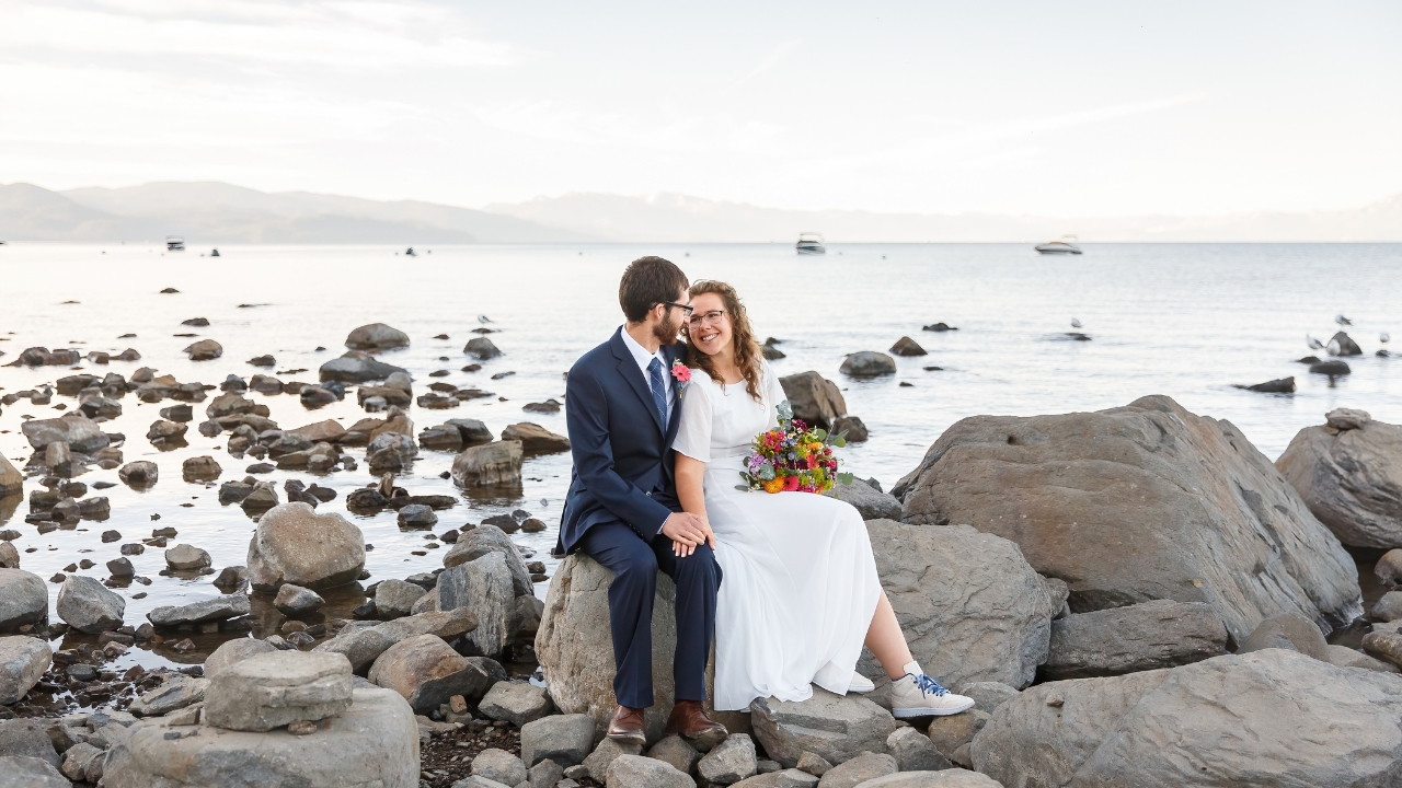 Photo of bride and groom sitting down, holding hands and looking at each other at their Lake Tahoe elopement