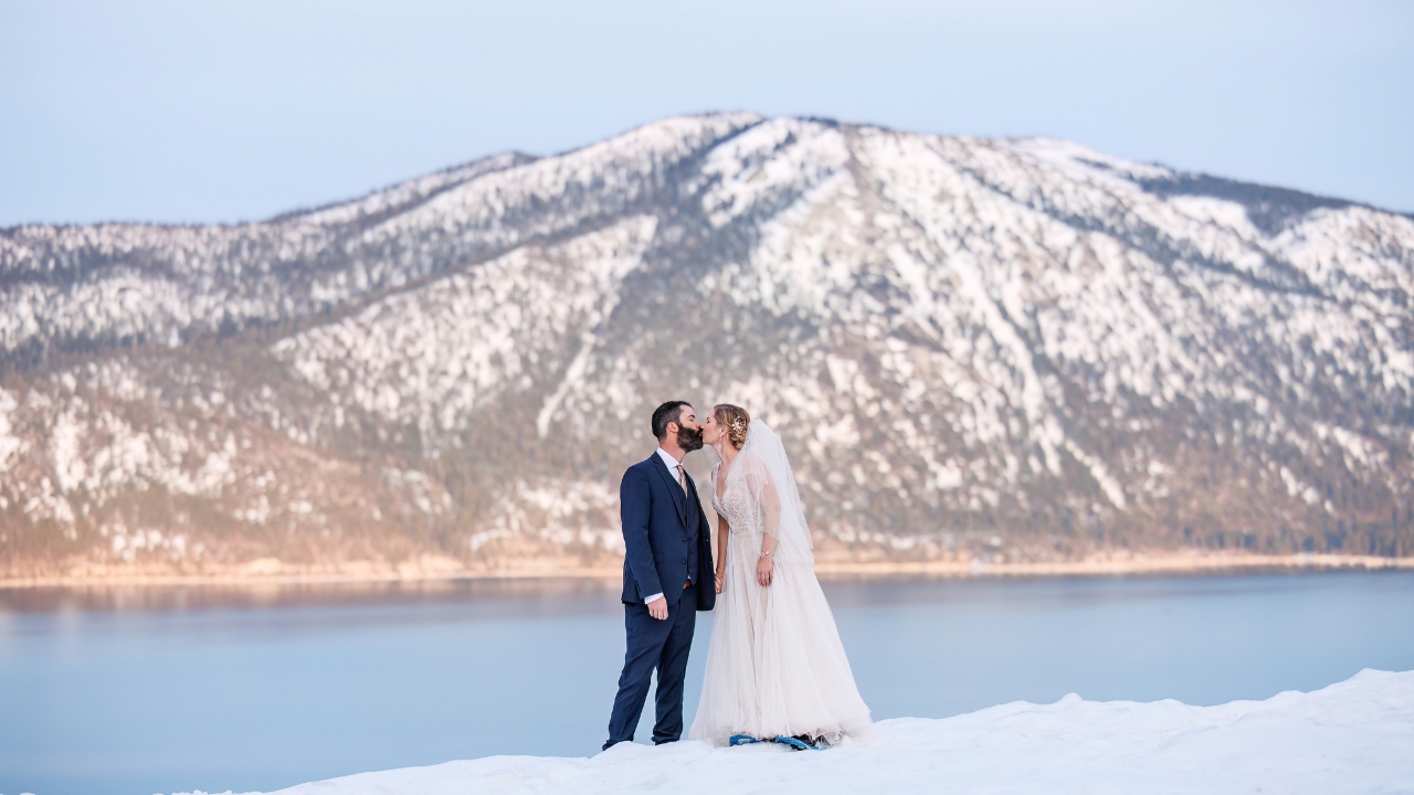 photo of bride and groom kissing at Lake Tahoe with a snowy mountain range behind them