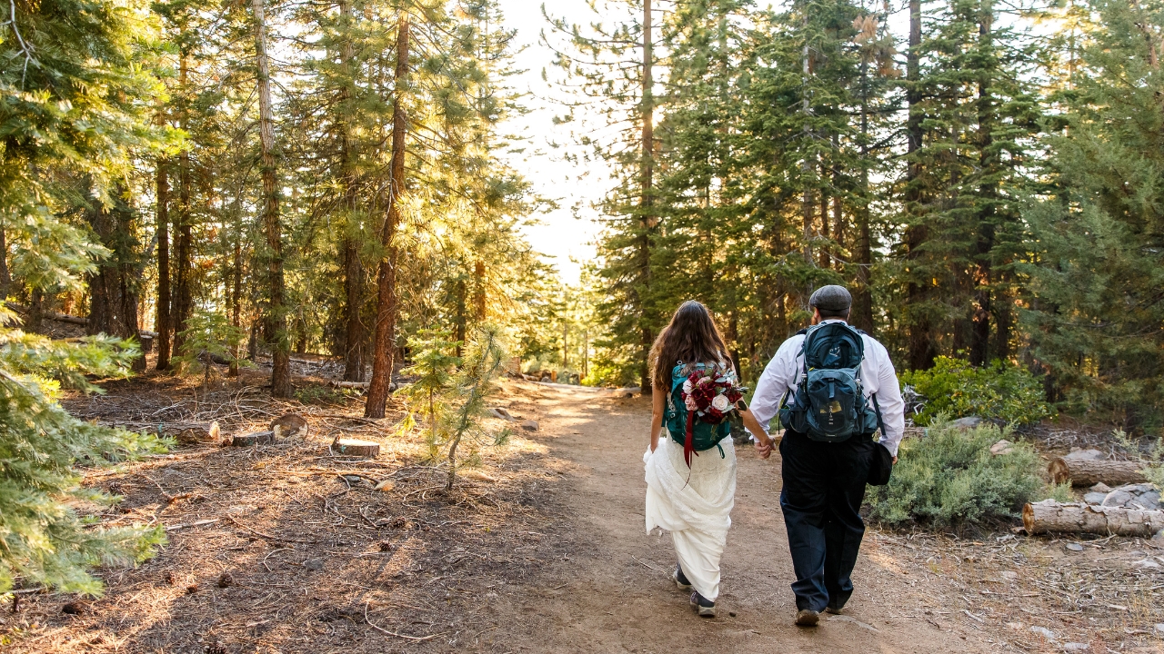 photo of bride and groom holding hands and hiking at their Lake Tahoe adventure elopement