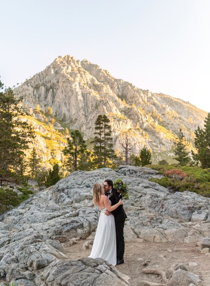photo of bride and groom kissing with mountain range behind them