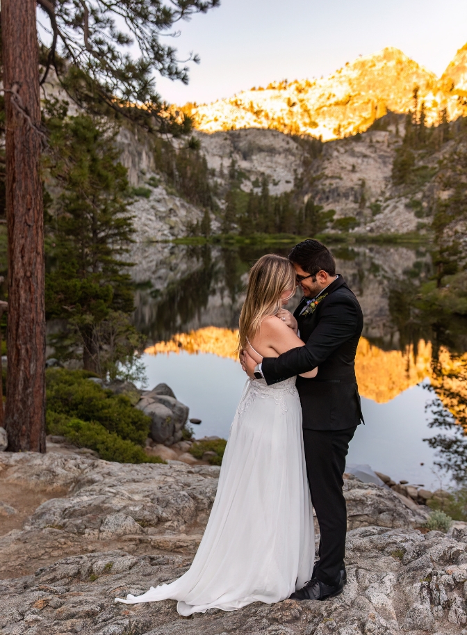 bride and groom holding each other in by lake at Lake Tahoe
