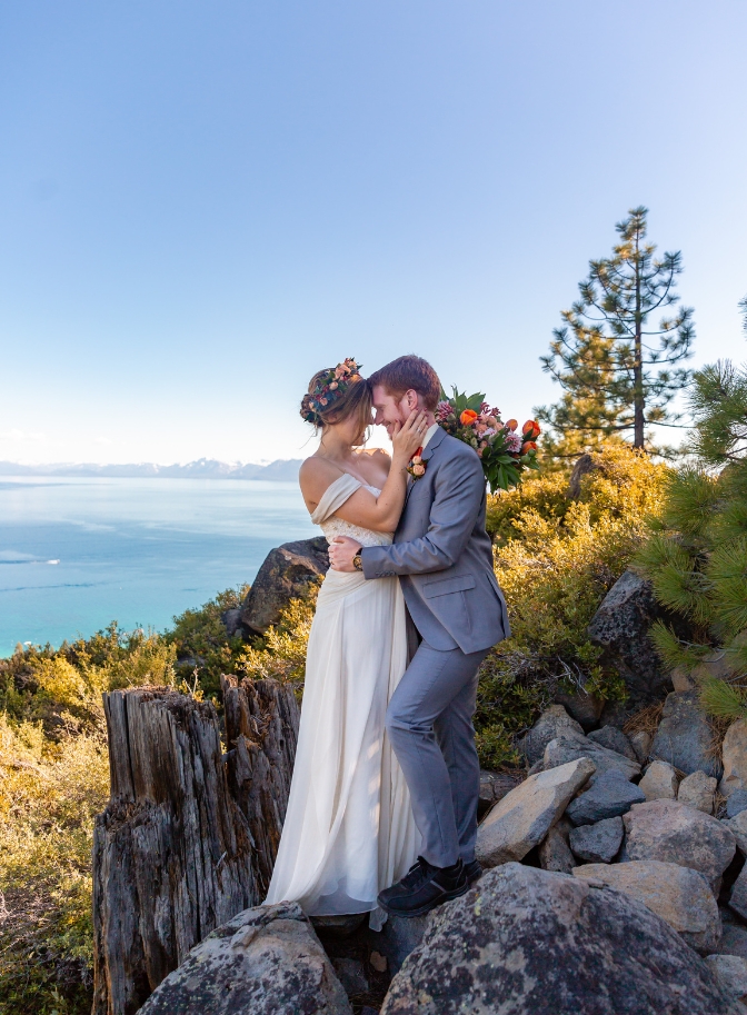 photo of bride holding grooms face as he holds her waist with Lake Tahoe behind them
