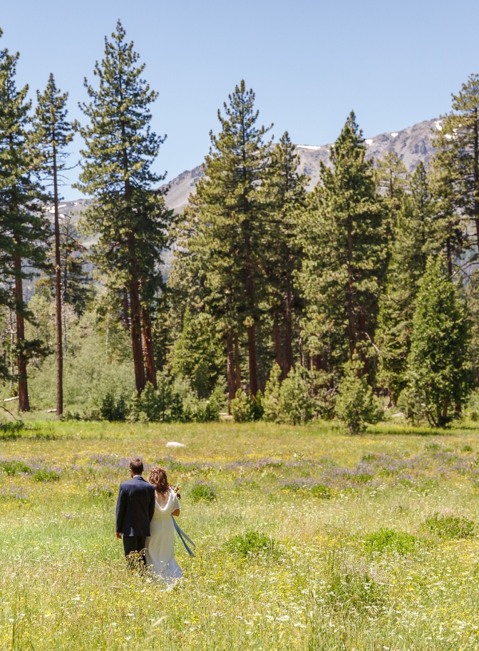 photo of bride and groom walking through a field of wildflowers for their Lake Tahoe elopement