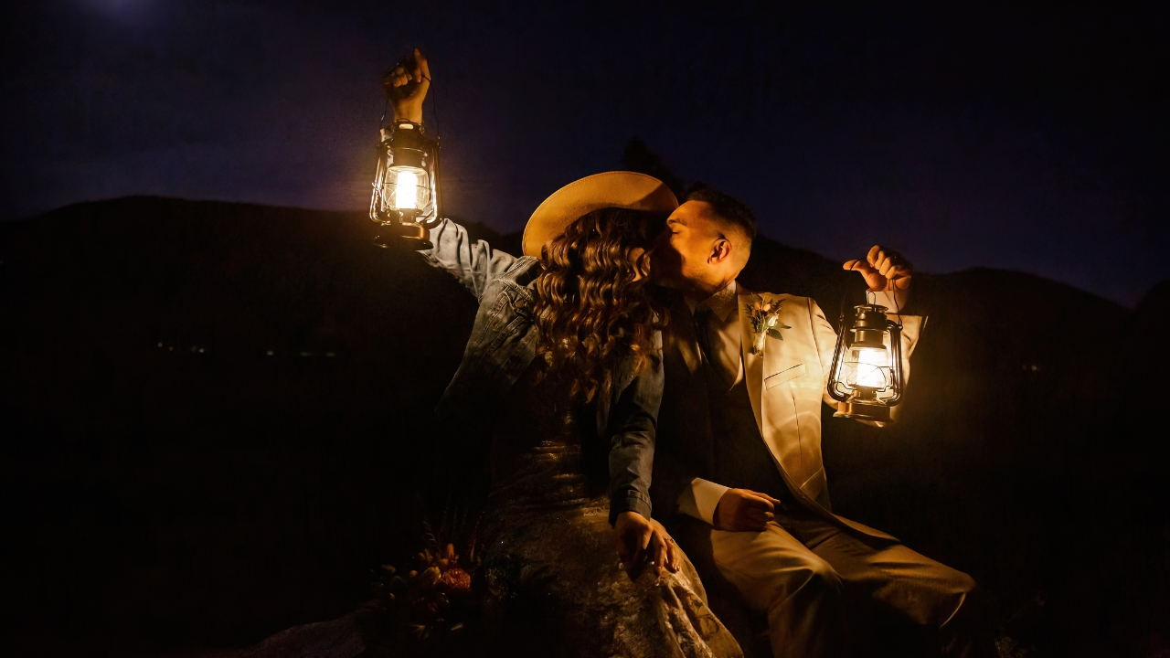 photo of bride and groom kissing on wedding night while holding lanterns