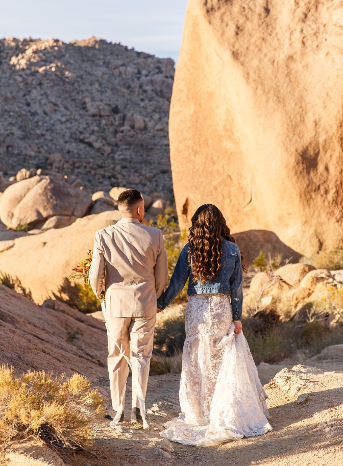 photo of bride and groom walking hand in hand down a trail