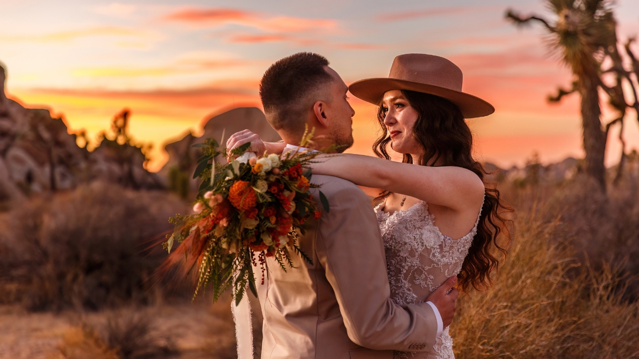 Photo of bride and groom looking into each other's eyes and embracing with the sunset behind them