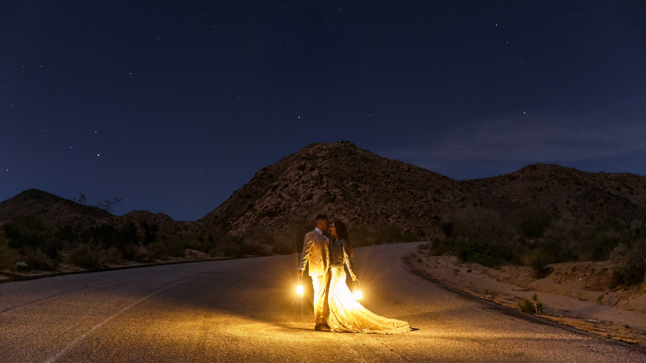 photo of bride and groom standing in street at night with lanterns, embracing