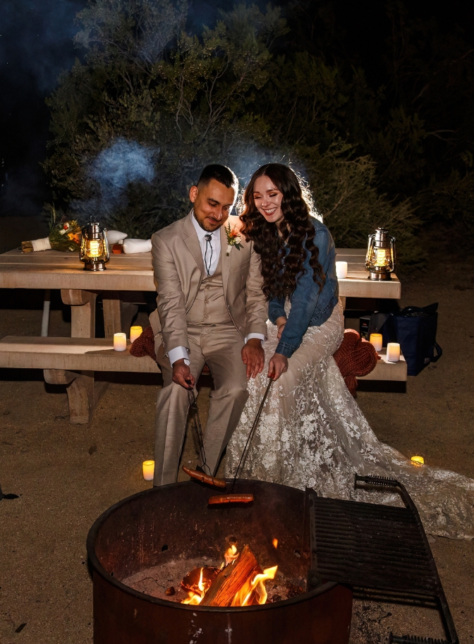 photo of bride and groom cooking hot dogs in a firepit on a picnic bench for their wedding night