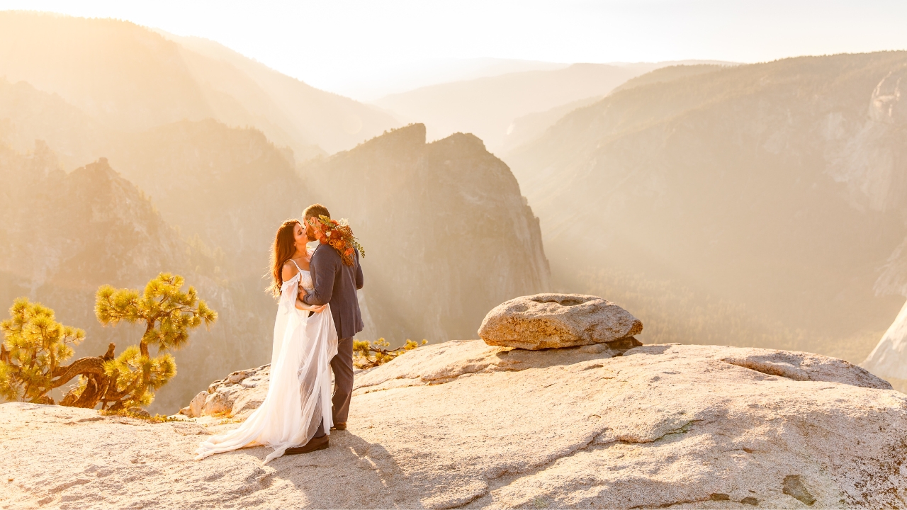 photo of bride and groom kissing with Sierra Nevada Mountains behind them at sunrise