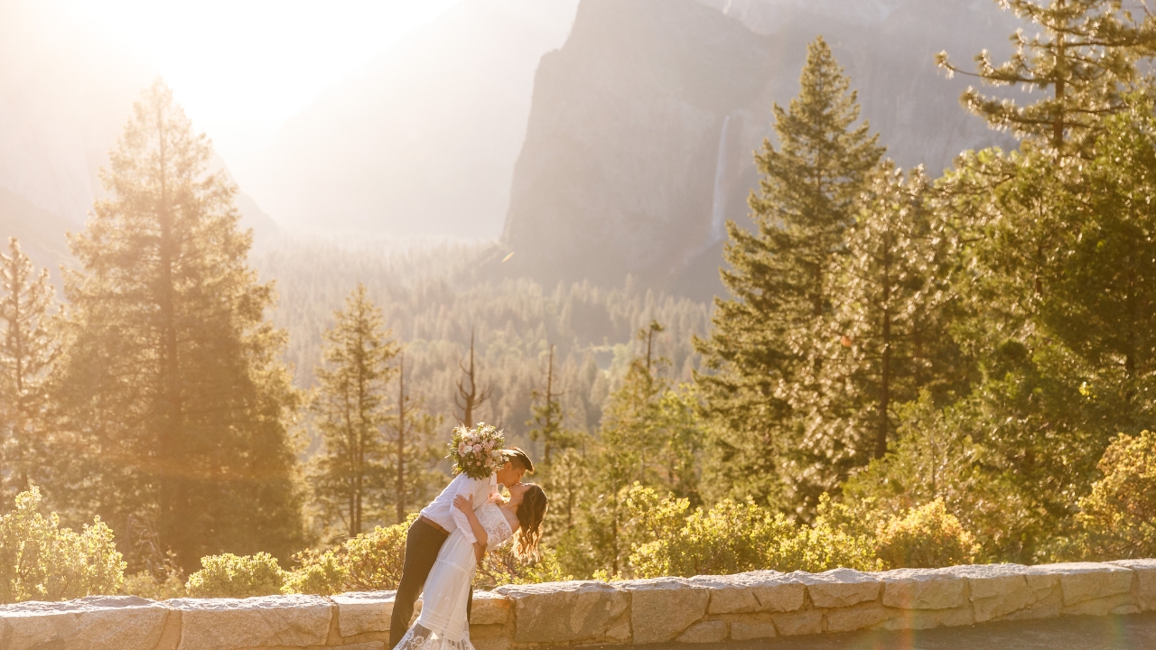 photo of groom dipping bride and kissing her at sunset with waterfall behind them on wedding day 