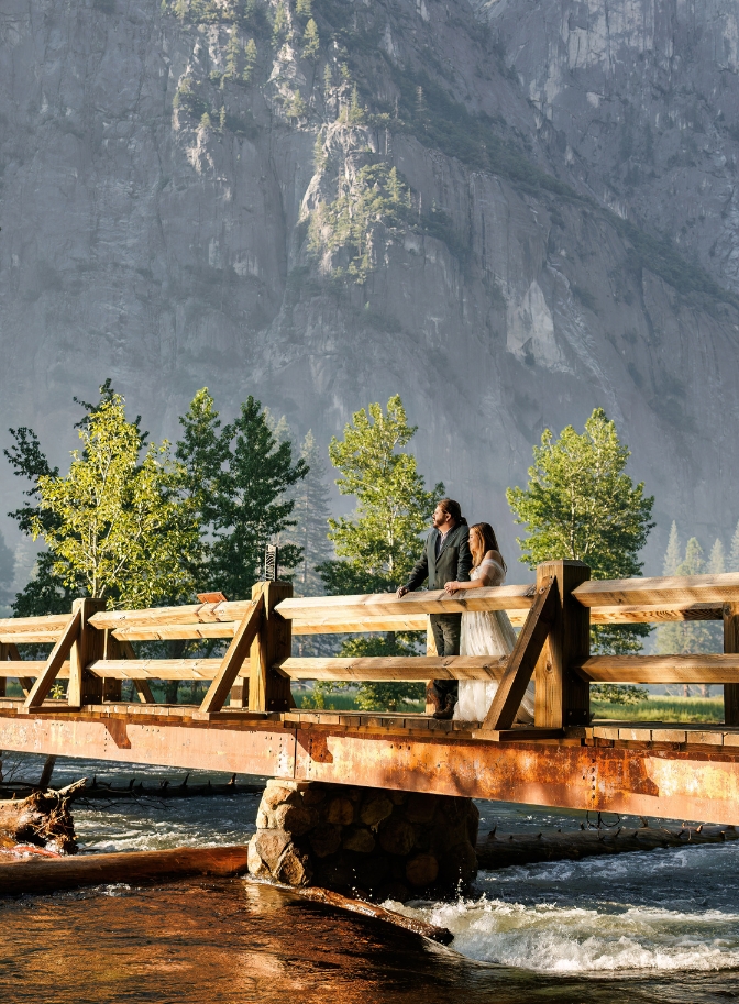 photo of bride and groom standing side by side looking out at bridge with rock face behind them for their elopement