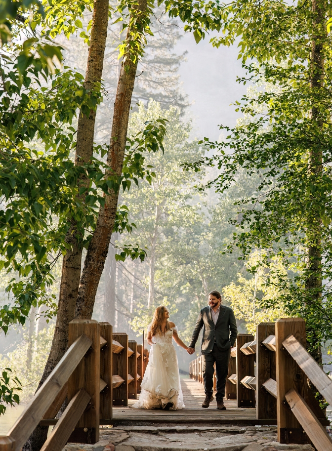 photo of bride and groom holding hands walking along bridge