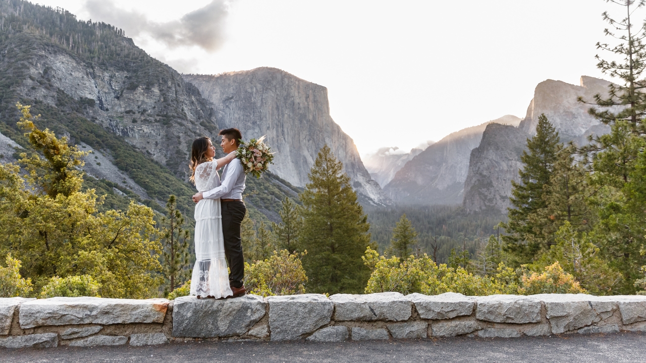 photo of bride and groom embracing while standing on a ledge at Yosemite National Park