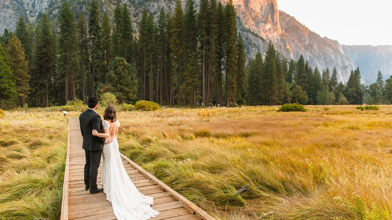 photo of bride and groom embracing while standing on wooden pathway in Yosemite