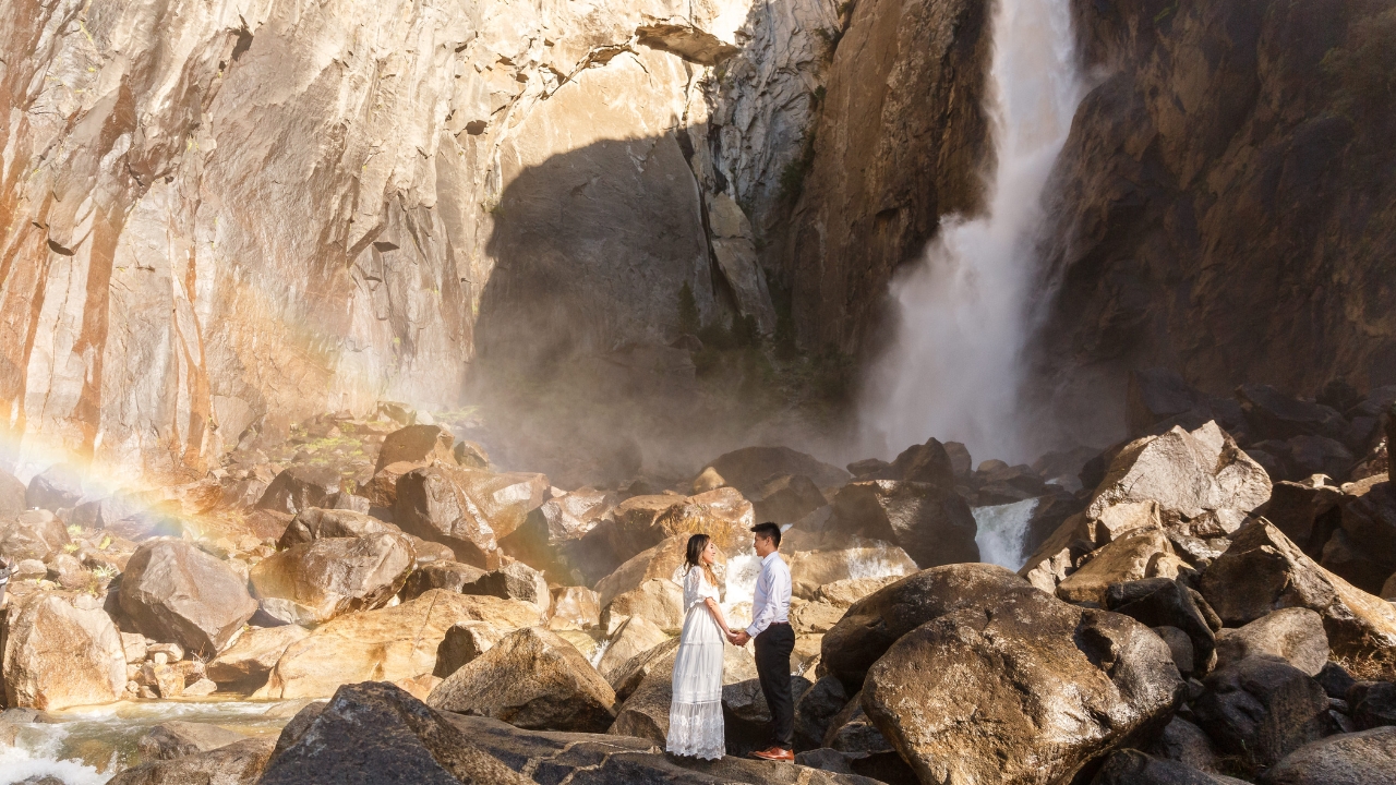 photo of bride and groom holding hands and staring into each others eyes with a waterfall behind them