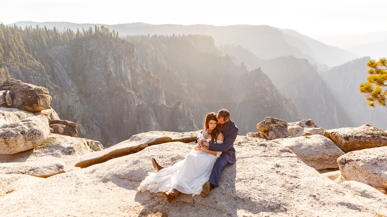 photo of bride and groom sitting on the ledge of Glacier Point Amphitheater for their wedding day