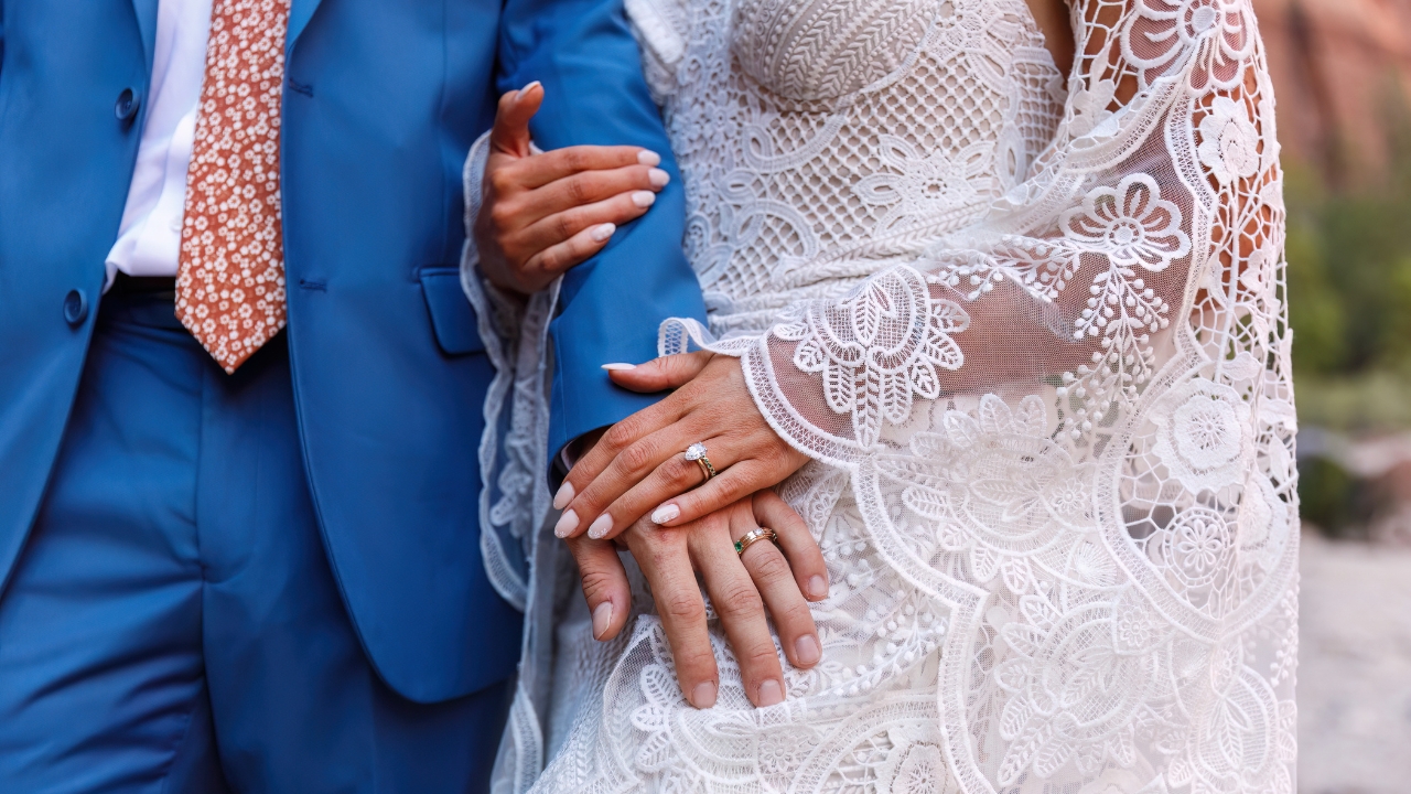 photo of bride and groom holding hands and showing off custom made rings