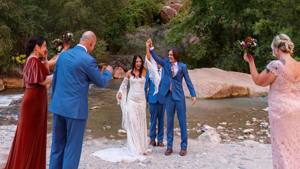 photo of bride and groom raising hands and celebrating at their Zion elopement in front of family and friends