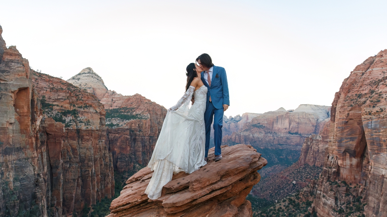 photo of bride and groom kissing with Zion Valley behind them