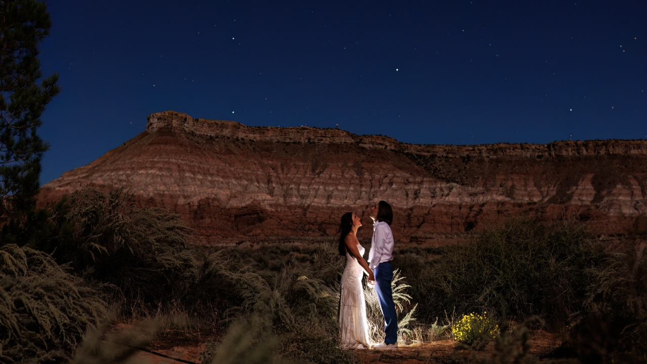 photo of bride and groom holding hands and looking up at the night sky in Zion