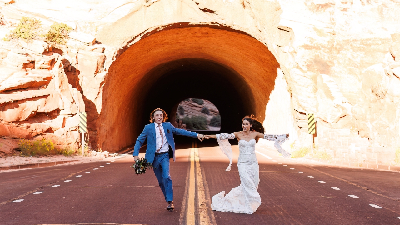 photo of bride and groom running down street with tunnel behind them for their Zion elopement