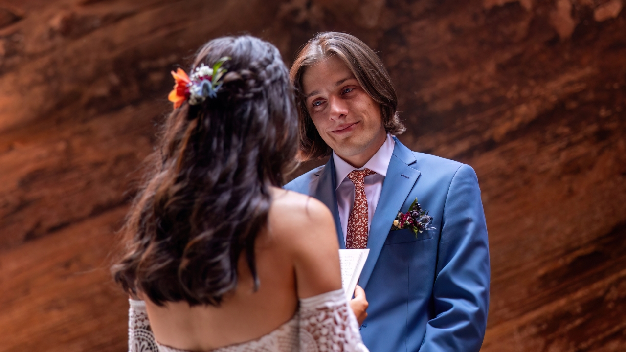 photo of groom looking at his bride adoringly as she reads her vows