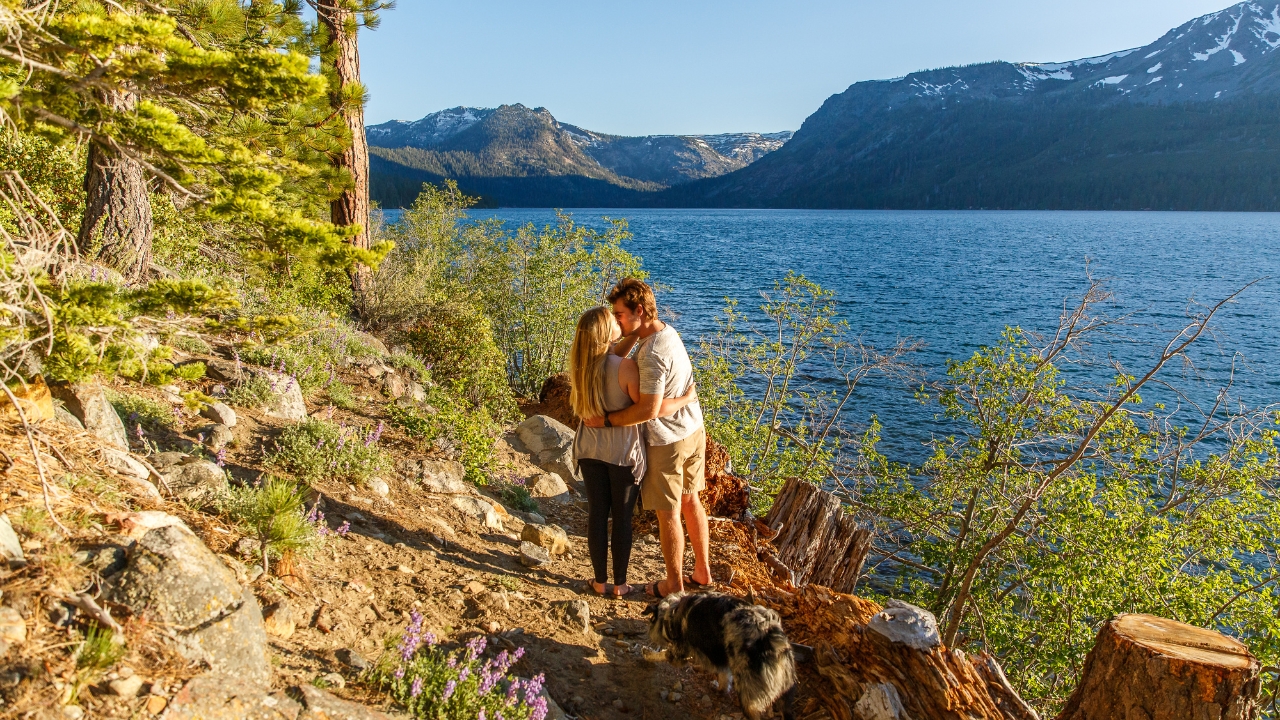 photo of couple kissing along a trail with Lake Tahoe in the background