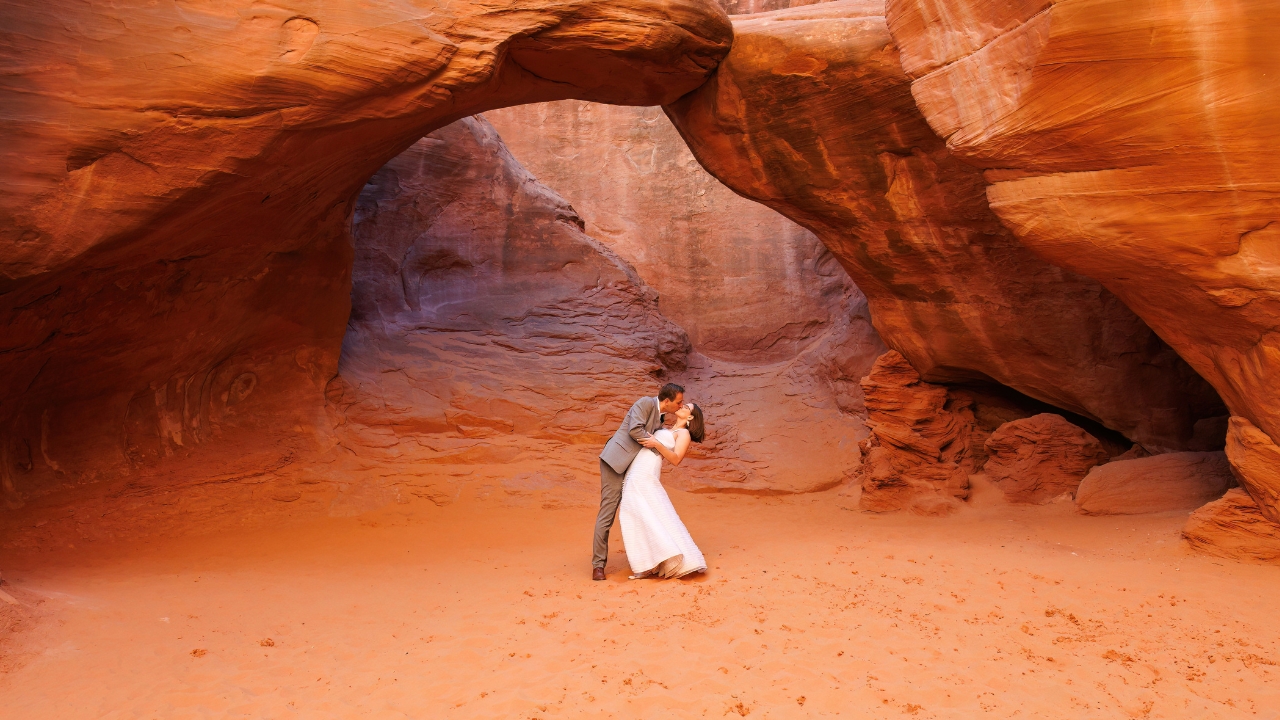 photo of groom dipping bride and kissing her under arch in Arches National Park