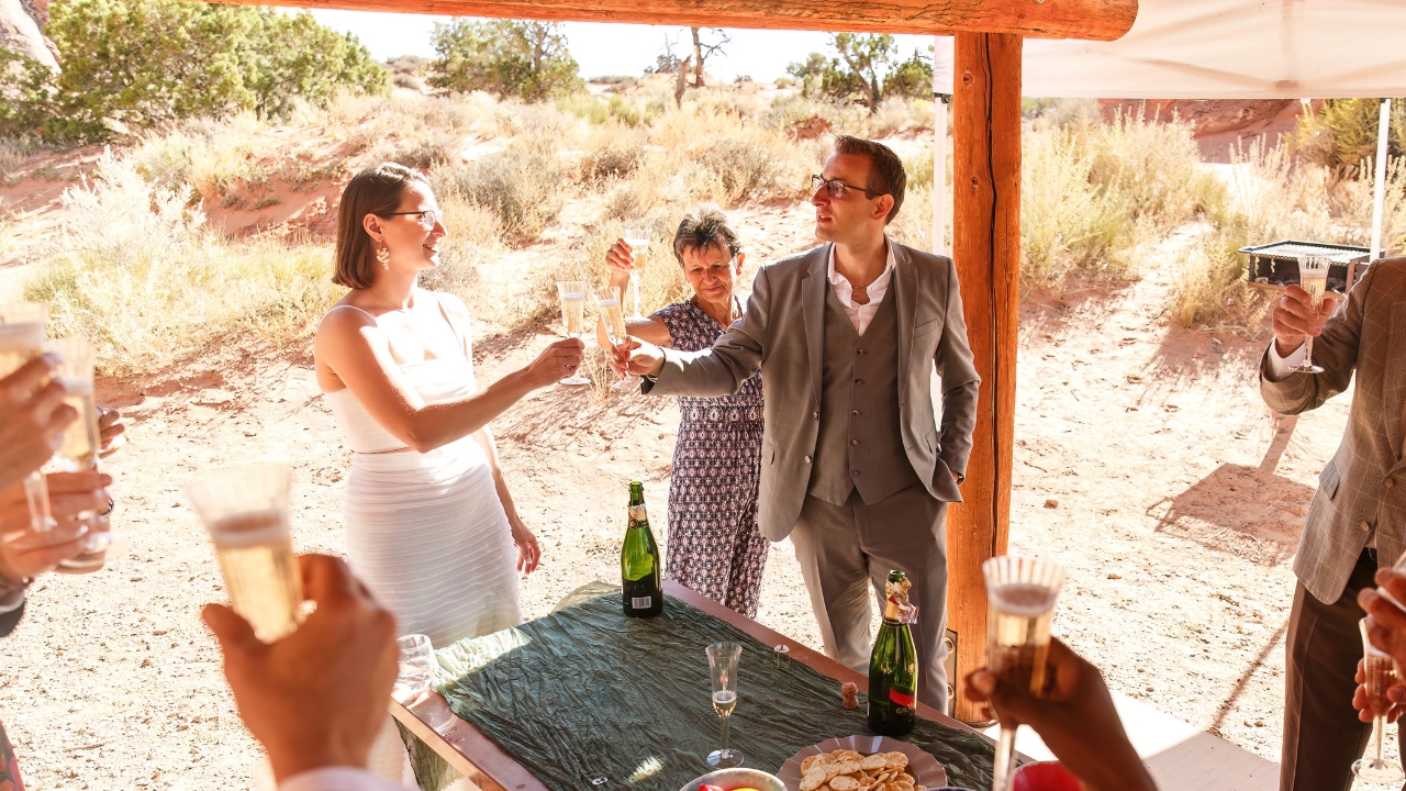 photo of bride and groom cheersing at elopement picnic with famiy